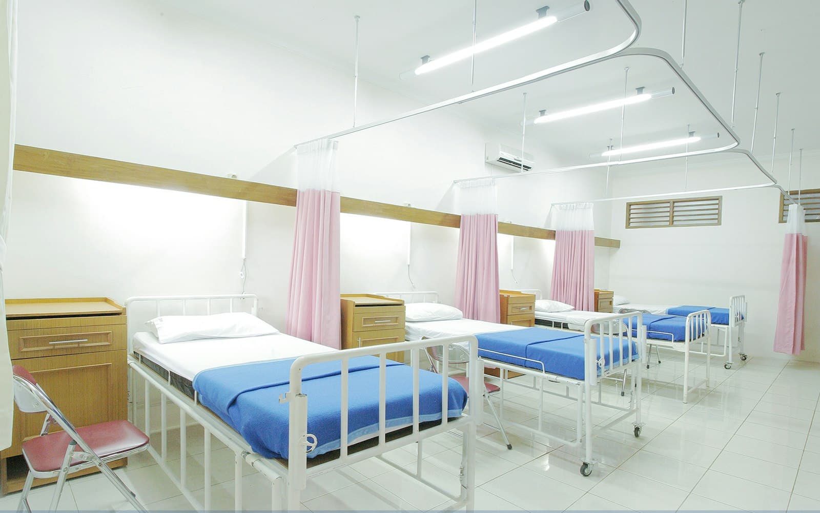 Unité d'hospitalisation lumineuse avec lits et rideaux de séparation